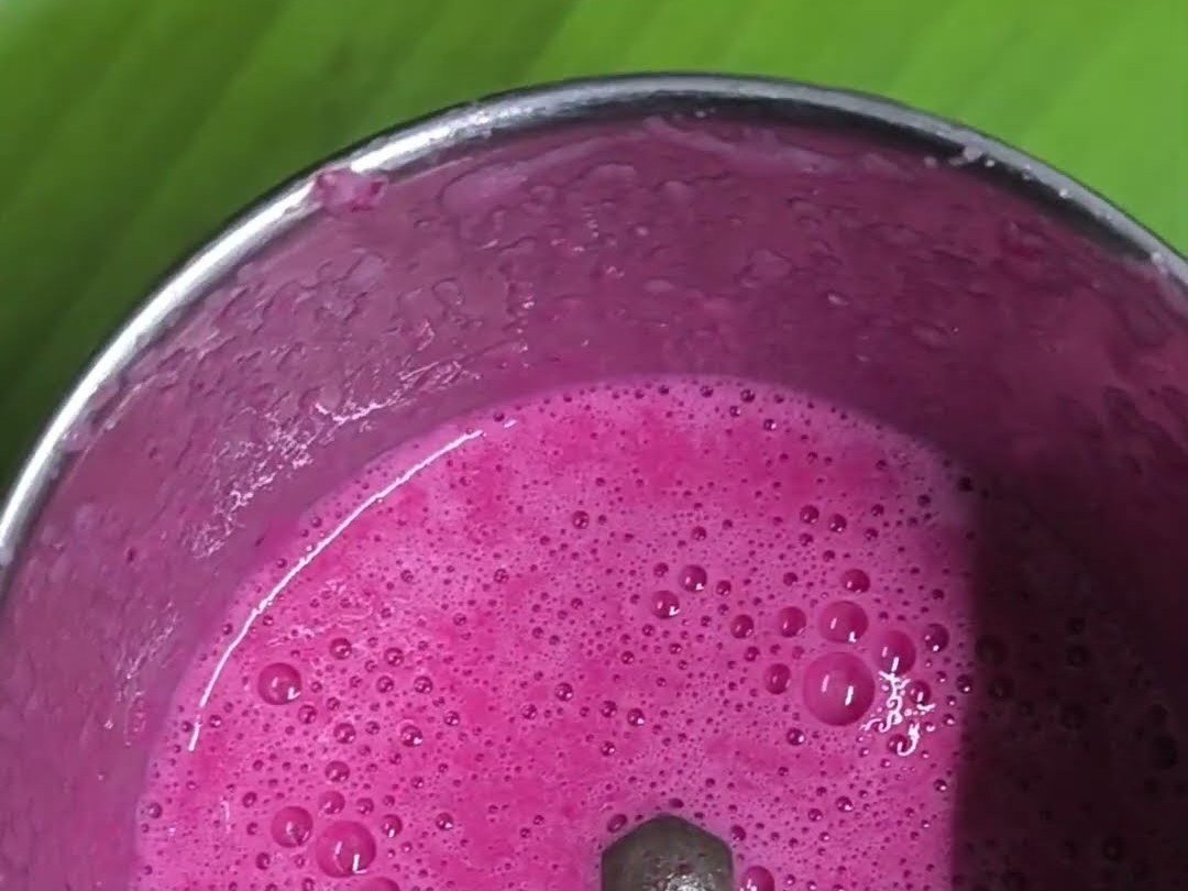 Bright pink karuppu ulunthu beetroot milk smoothie in a steel mixer jar