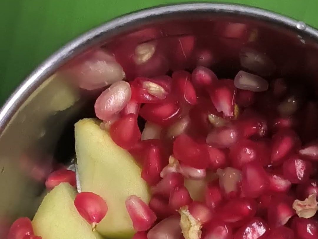 Pomegranate seeds and steamed apple pieces in a steel mixer jar